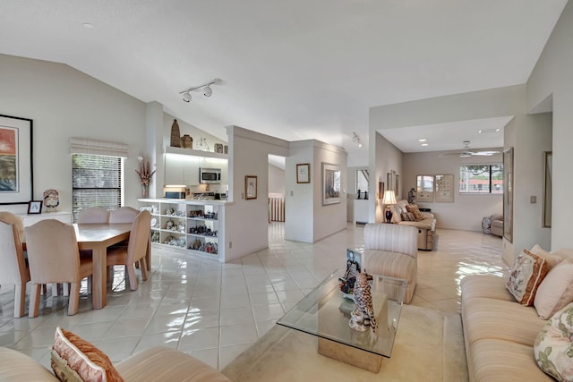 tiled living room featuring vaulted ceiling, track lighting, and ceiling fan