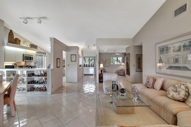 living room with vaulted ceiling, track lighting, ceiling fan, and light tile patterned flooring