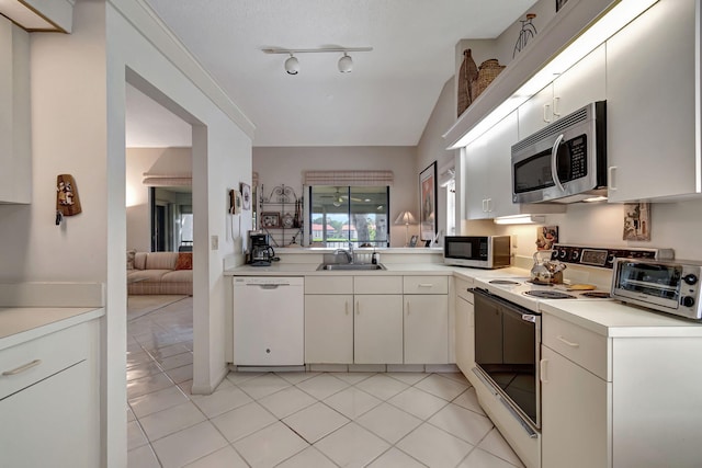 kitchen featuring sink, vaulted ceiling, light tile patterned floors, kitchen peninsula, and white appliances