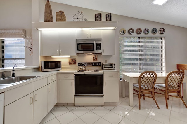 kitchen featuring vaulted ceiling, light tile patterned flooring, sink, white cabinets, and white appliances