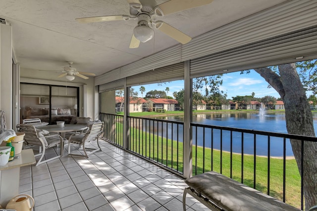 unfurnished sunroom with ceiling fan and a water view