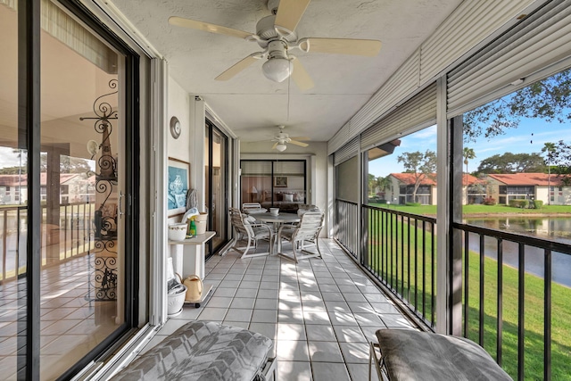 unfurnished sunroom featuring ceiling fan and a water view