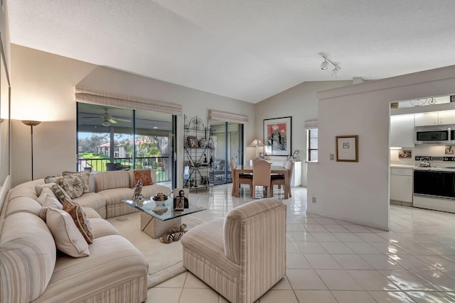 living room featuring ceiling fan, vaulted ceiling, a textured ceiling, and light tile patterned floors