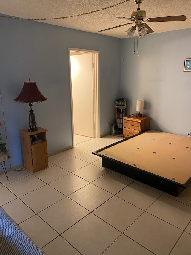 unfurnished bedroom with light tile patterned flooring, ceiling fan, and a textured ceiling