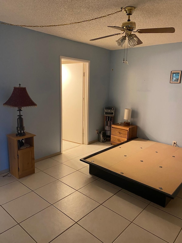 unfurnished bedroom with light tile patterned floors, a textured ceiling, and ceiling fan