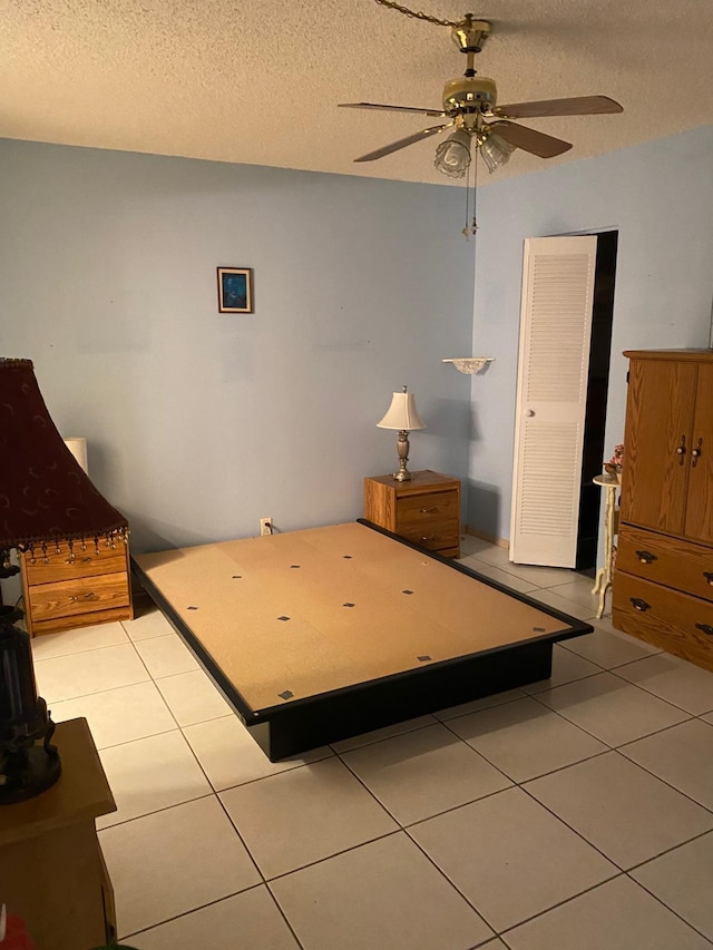 tiled bedroom with ceiling fan and a textured ceiling