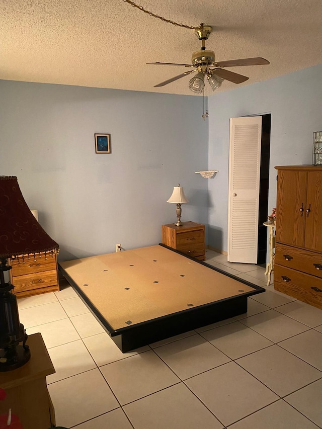 unfurnished bedroom with ceiling fan, a textured ceiling, and light tile patterned floors