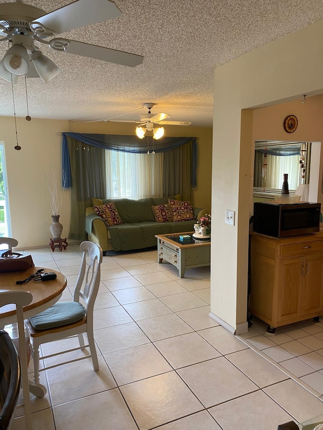 tiled living room with ceiling fan and a textured ceiling