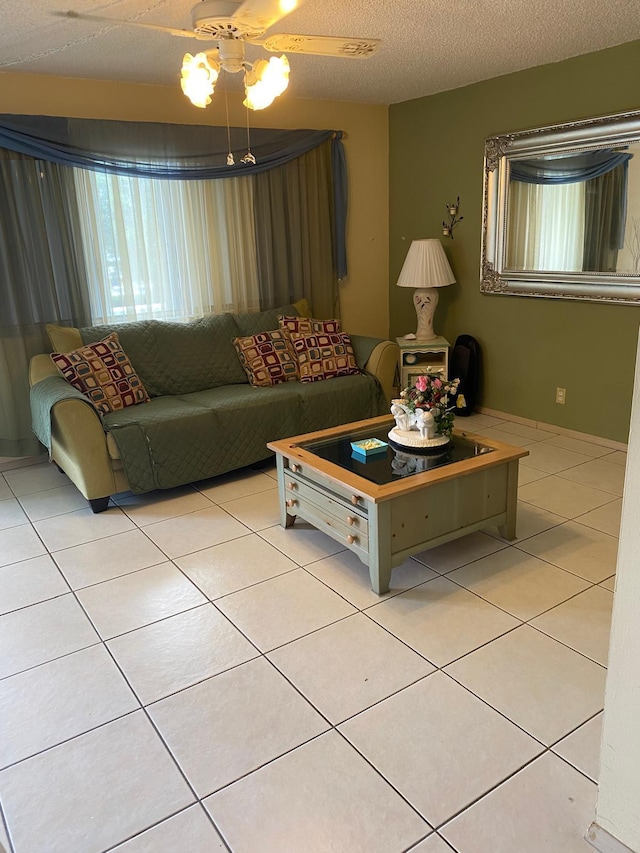 living room with ceiling fan, light tile patterned floors, and a textured ceiling