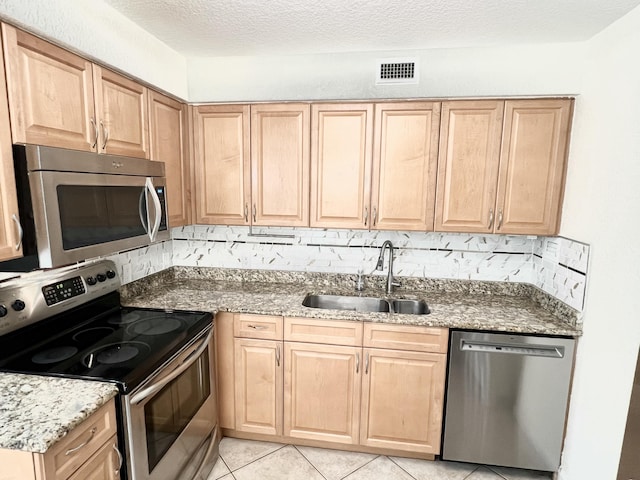 kitchen with light brown cabinetry, sink, decorative backsplash, stainless steel appliances, and a textured ceiling