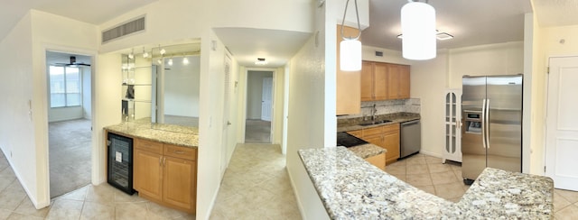 kitchen featuring sink, hanging light fixtures, stainless steel appliances, light stone counters, and wine cooler