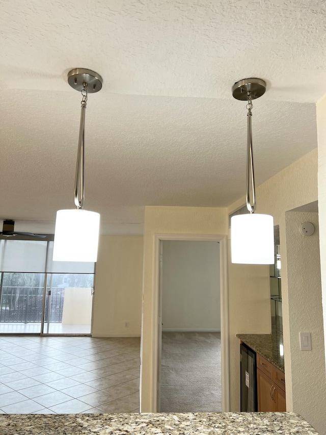 interior space featuring hanging light fixtures, dark stone countertops, and a textured ceiling