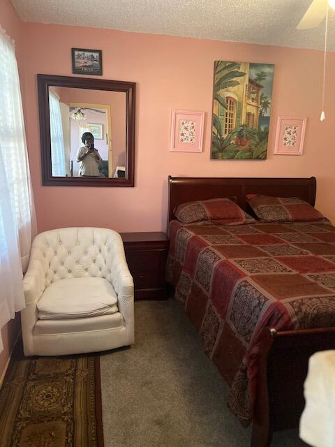 bedroom featuring a textured ceiling, carpet floors, and ceiling fan