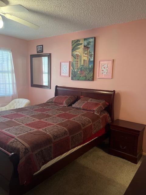 carpeted bedroom with ceiling fan and a textured ceiling