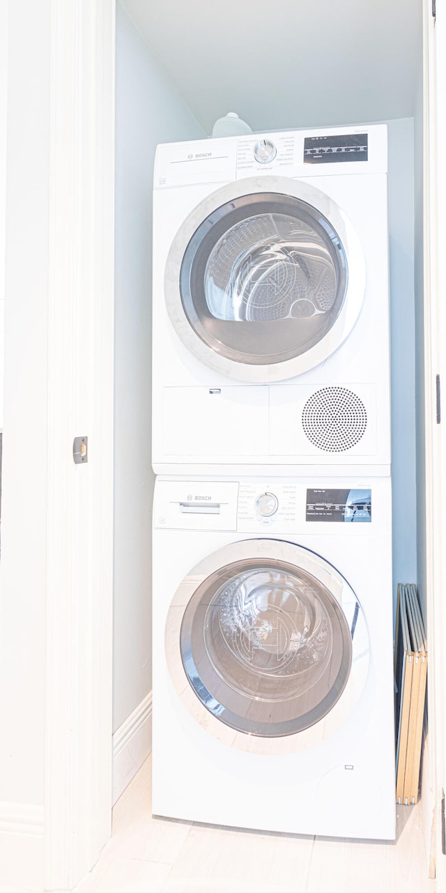 laundry area with stacked washer / dryer and light tile patterned floors