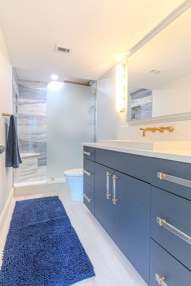 bathroom with vanity, tile patterned flooring, toilet, and tiled shower