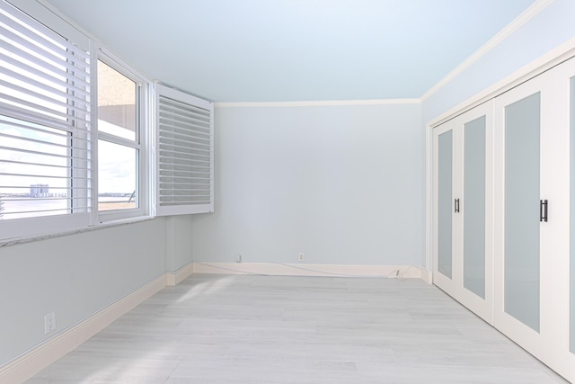 empty room with light wood-type flooring, a healthy amount of sunlight, and crown molding