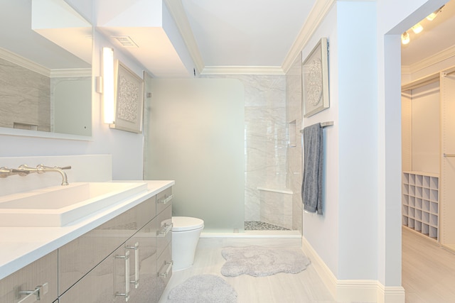 bathroom featuring crown molding, a tile shower, vanity, and toilet