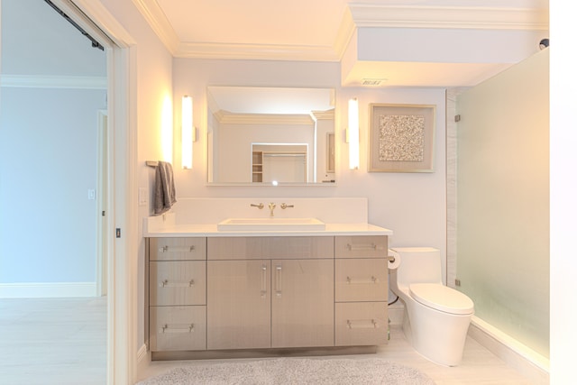 bathroom with ornamental molding, vanity, a shower with shower door, and toilet