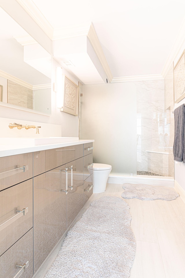 bathroom with crown molding, a shower with door, vanity, and toilet