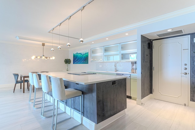 kitchen featuring sink, ornamental molding, a kitchen island, decorative light fixtures, and dishwasher