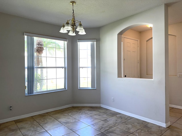 tiled spare room with an inviting chandelier and a textured ceiling