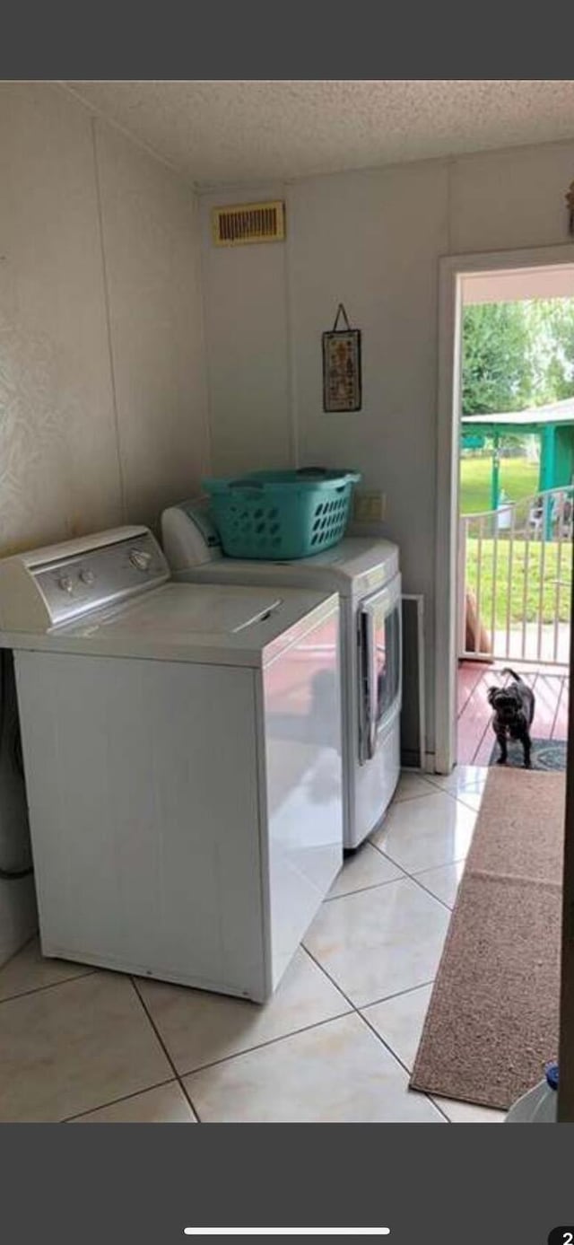 laundry area with washing machine and dryer, light tile patterned floors, and a textured ceiling