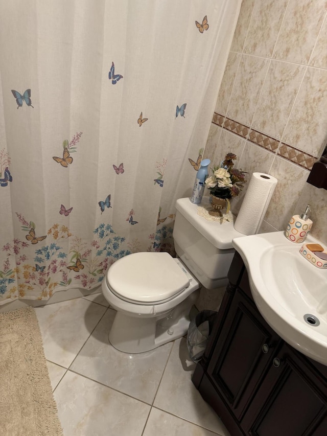 bathroom with tile patterned flooring, vanity, toilet, and tile walls