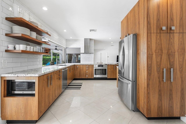 kitchen featuring appliances with stainless steel finishes, sink, backsplash, and wall chimney range hood