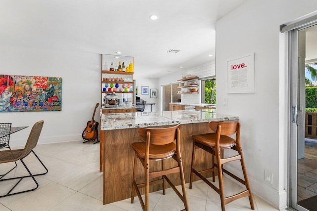 bar featuring light stone counters and light tile patterned flooring