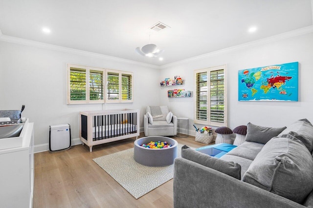 bedroom with a crib, light hardwood / wood-style floors, crown molding, and sink