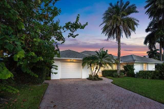 single story home featuring a garage and a lawn