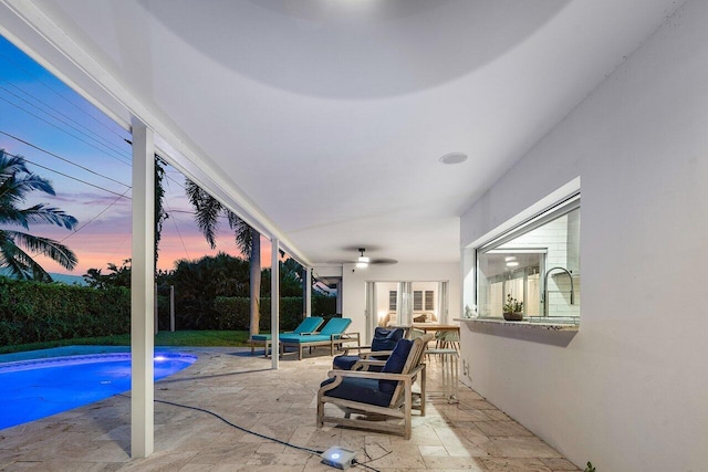 patio terrace at dusk featuring ceiling fan and a fenced in pool