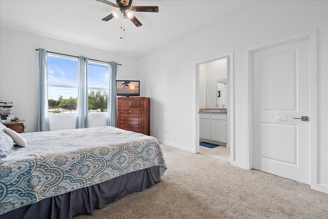 bedroom featuring connected bathroom, sink, light carpet, and ceiling fan