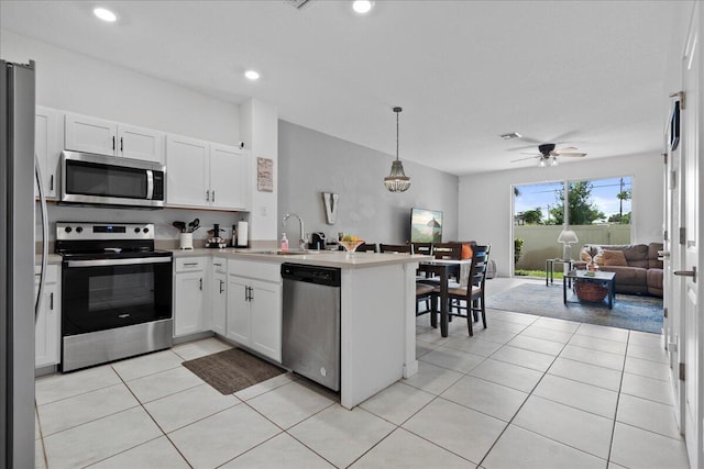 kitchen with hanging light fixtures, stainless steel appliances, sink, white cabinets, and ceiling fan