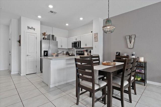 kitchen featuring hanging light fixtures, light tile patterned floors, appliances with stainless steel finishes, white cabinetry, and sink