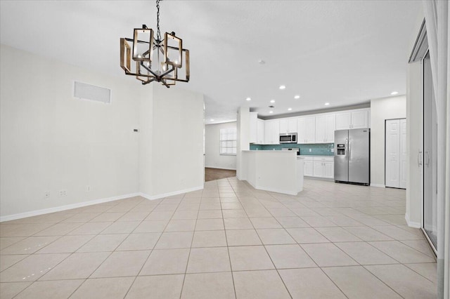 kitchen with white cabinets, hanging light fixtures, light tile patterned floors, appliances with stainless steel finishes, and a notable chandelier