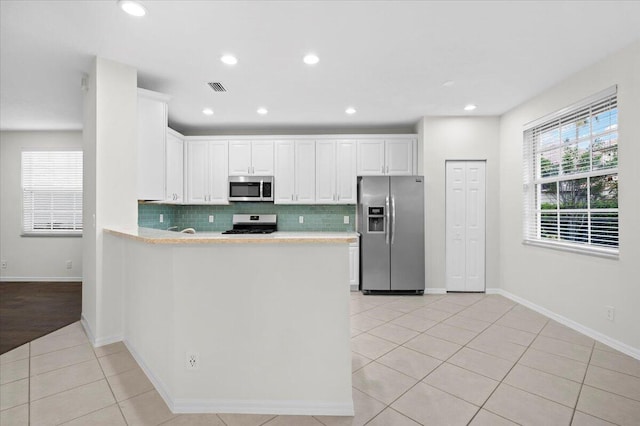 kitchen featuring white cabinets, stainless steel appliances, backsplash, and light tile patterned floors