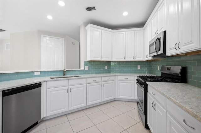 kitchen featuring appliances with stainless steel finishes, sink, light tile patterned floors, and white cabinets