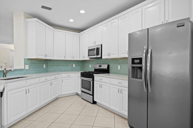 kitchen with stainless steel appliances, white cabinets, light tile patterned floors, and sink