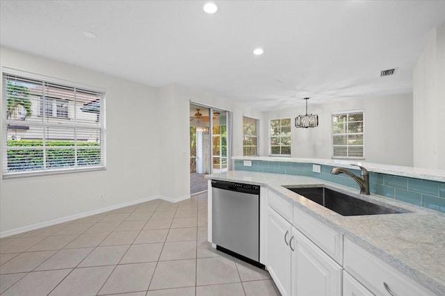 kitchen with light tile patterned flooring, hanging light fixtures, sink, stainless steel dishwasher, and white cabinetry