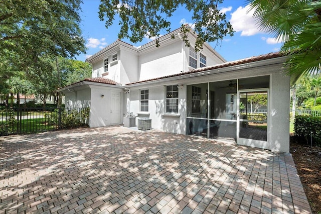 back of property with a sunroom, central AC unit, and a patio area