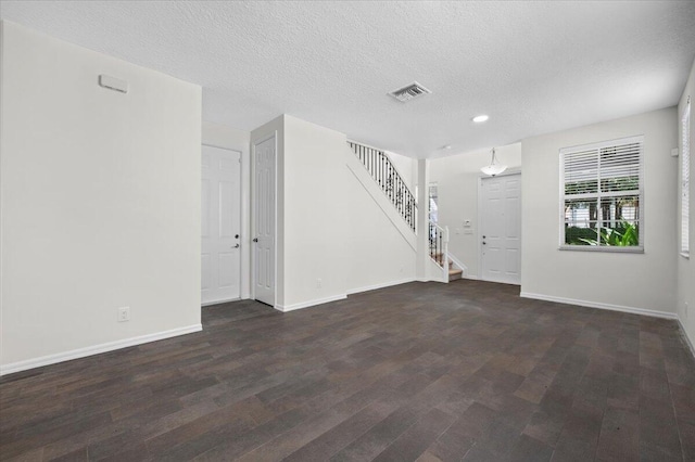 unfurnished living room with a textured ceiling and dark wood-type flooring