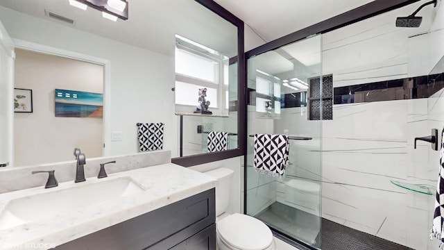 bathroom with vanity, a shower with shower door, and toilet