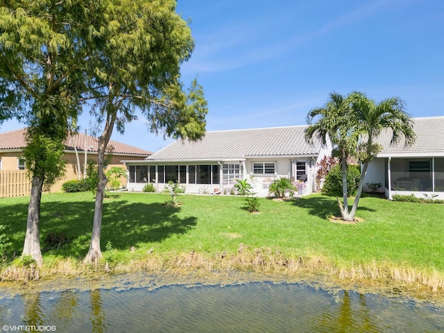 back of house featuring a sunroom, a water view, and a lawn