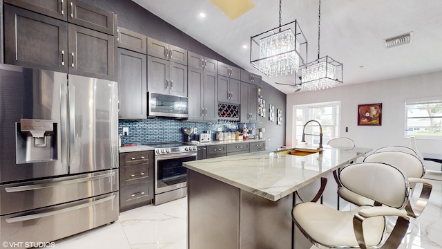 kitchen featuring light stone countertops, a center island with sink, appliances with stainless steel finishes, and a healthy amount of sunlight