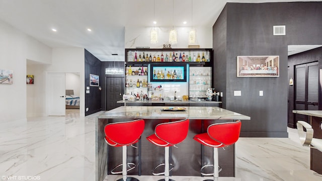 bar with hanging light fixtures and light stone counters