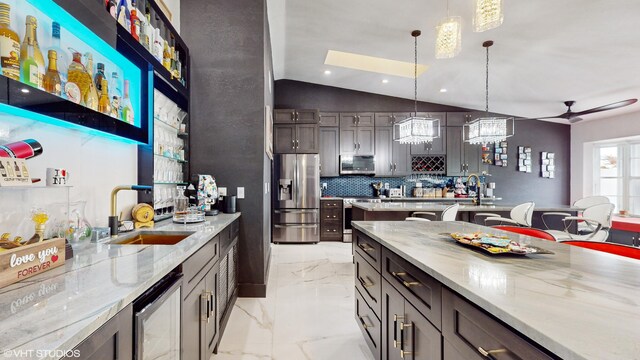 kitchen with light stone countertops, sink, stainless steel appliances, and decorative light fixtures