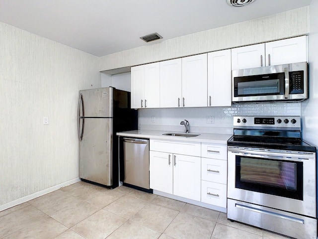 kitchen with sink, white cabinetry, decorative backsplash, stainless steel appliances, and light tile patterned floors