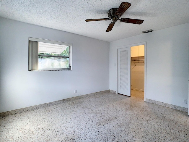 unfurnished bedroom featuring a textured ceiling, a spacious closet, ceiling fan, and a closet